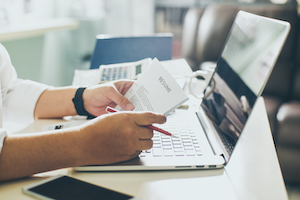 Person holding a employment verification over a computer